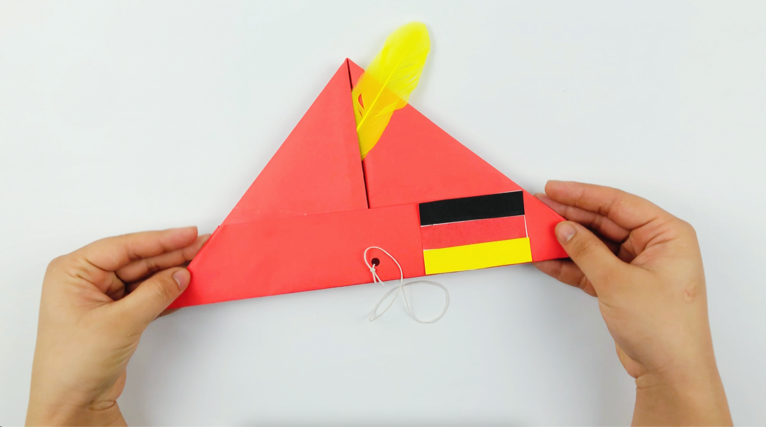 Hands holding a red and yellow paper Bavarian Hat craft