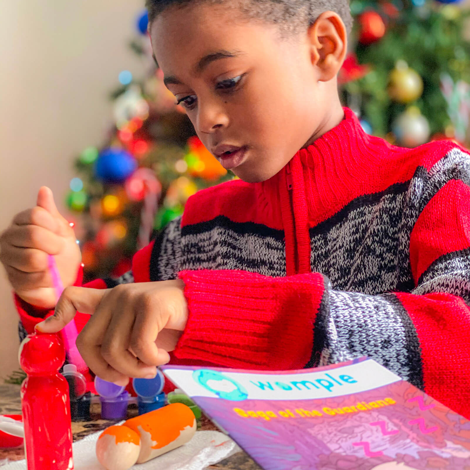 Little boy playing in front of Christmas tree with his WompleBox