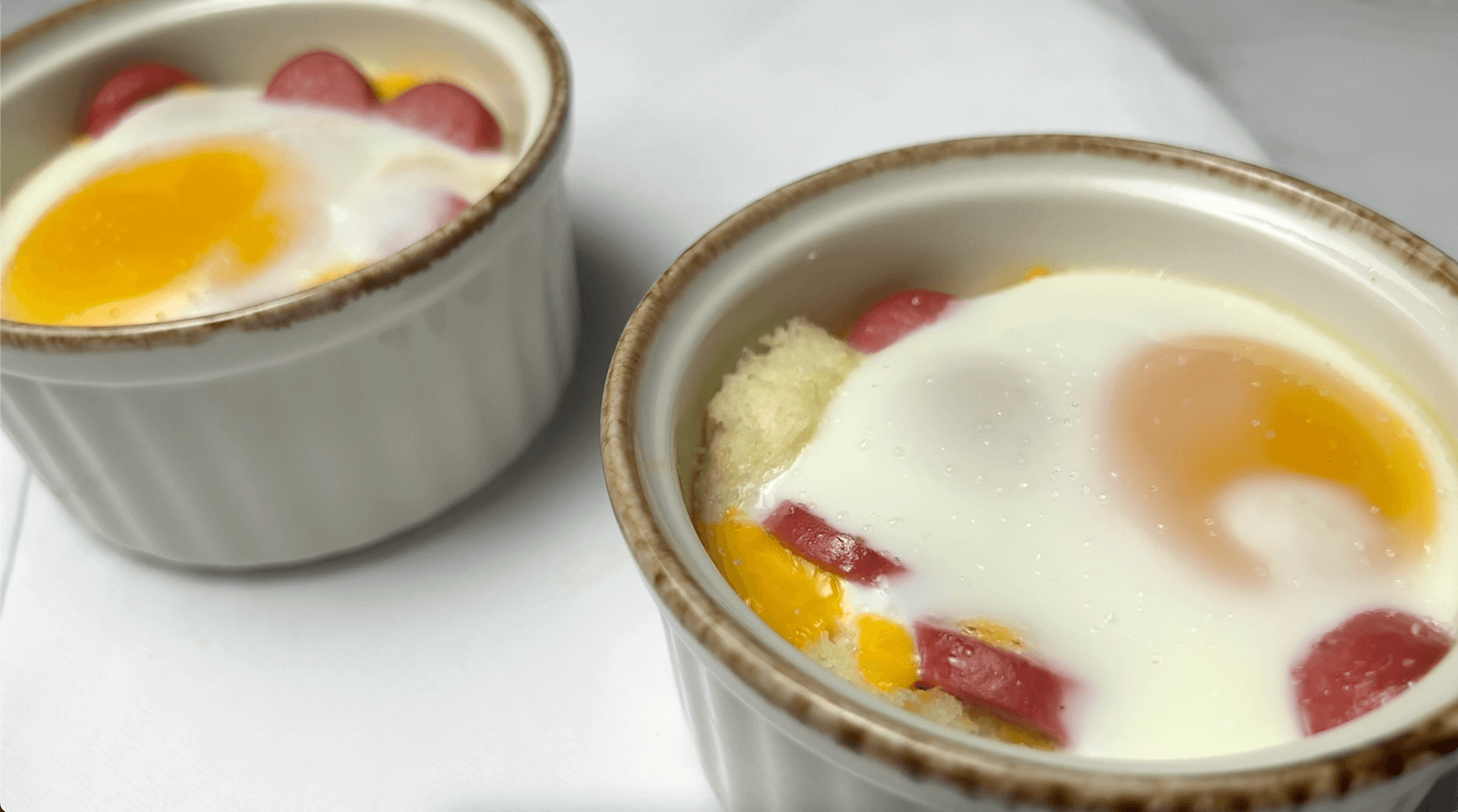 Two cheesy oeufs en cocotte in ramekins