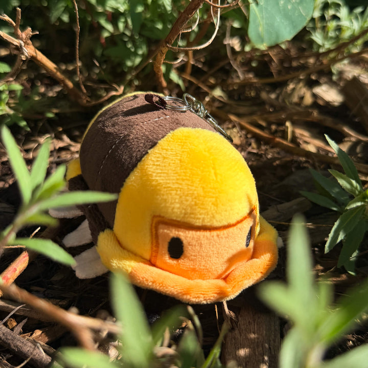 Plush toy rubber ducky isopod keychain in a natural setting with greenery