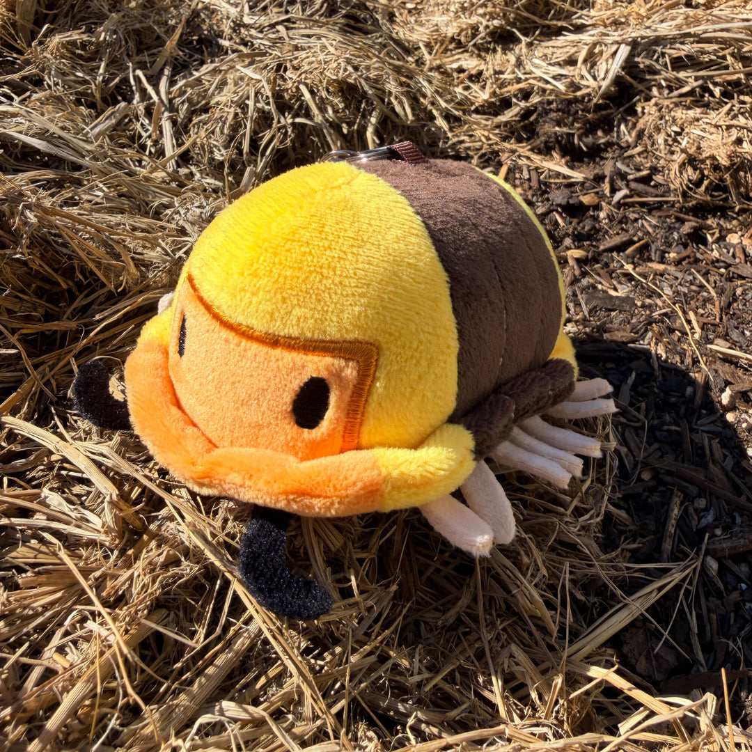 Plush rubber ducky isopod keychain toy on mulch and hay
