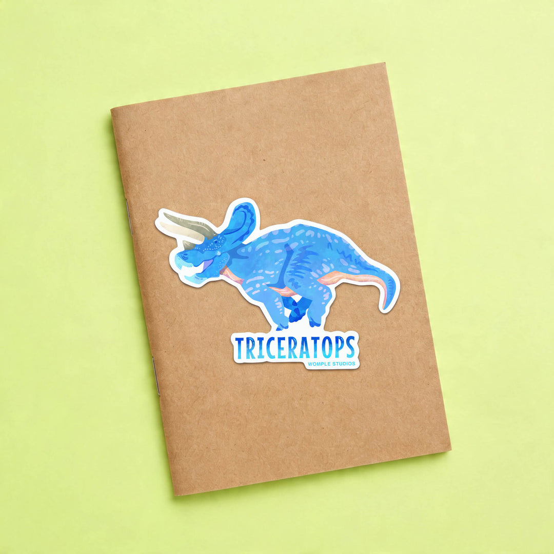Notebook with a blue Triceratops sticker on a green background