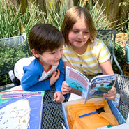Girl reading to younger brother from WompleBox: Sri Lanka book