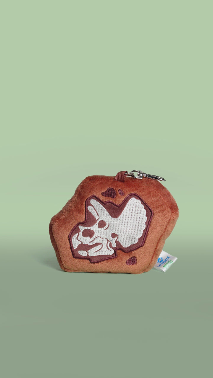 Brown triceratops dinosaur fossil skull plush toy bag charm on a white background rotating